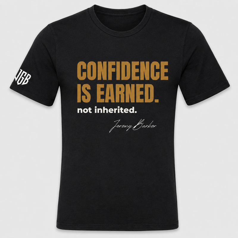 Quoted T&rsquo;s by Jeremy Barker. Confidence Is Earned, Not Inherited. Black short-sleeve unisex tee with gold and white print and JGB sleeve logo. Made in USA. From the Quoted T&rsquo;s collection of 16 mindset tees at $50 each