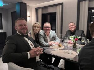 Jeremy Barker-Group of people dining together, smiling at a restaurant table.